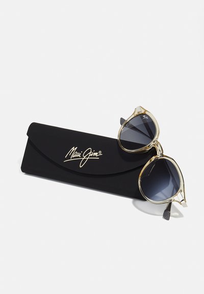 Maui Jim sunglasses with a golden frame and dark gray lenses, displayed on a black case featuring embossed logo and curved design.