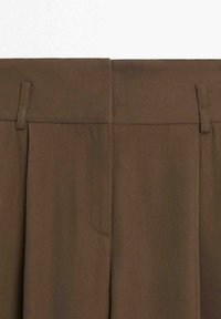 Pantalon marron taille haute avec passants pour ceinture et fermeture éclair frontale cachée, fabriqué en tissu texturé.