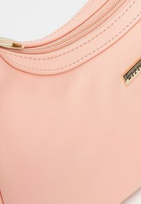 Borsa a tracolla sintetica rosa con una texture liscia, caratterizzata da una cerniera dorata e un piccolo marchio metallico con il nome del brand.