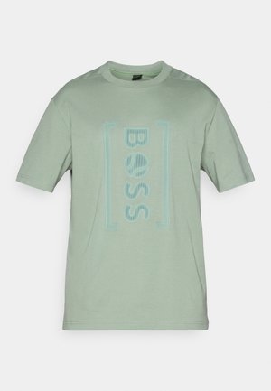Zelena bombažna majica s kratkimi rokavi, ki na sprednji strani vključuje svetlo modro logotip „BOSS“ in pravokotno obrobo. Gladka tekstura.