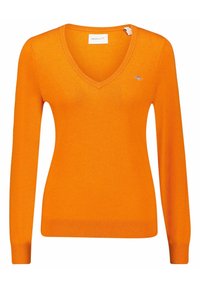 Oranžový svetr s výstřihem do V a dlouhými rukávy, vyrobený z měkkého materiálu. Má malé logo na hrudi a žebrované manžety a lem.