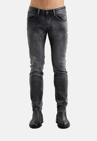 Jeans in denim nero con vestibilità slim, dotati di cinque tasche, finitura sbiadita e cuciture a contrasto. Abbinati a stivaletti alla caviglia in pelle nera.