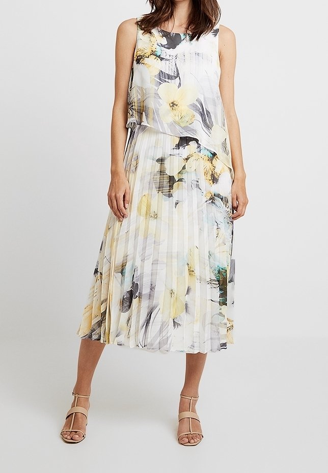 Sukienka z fałdami w kwiatowy wzór w odcieniach żółci i szarości. Lekka, bez rękawów, z warstwowym topem i płynącą sylwetką.