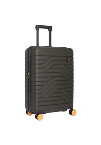Valigia grigia rigida con design a onde testurizzate, manico retrattile, dettagli arancioni sulle ruote e chiusura con cerniera.