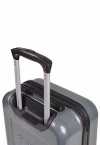 Grå hårdskal resväska med ett svart texturerat handtag och utdragbara aluminiumstänger; har ett blixtlås längs den övre kanten.