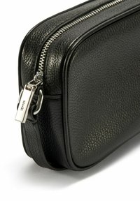 Czarna skórzana kosmetyczka o teksturowanym wykończeniu, z metalowym suwakiem i uchwytem, prostokątny kształt i elegancki design.