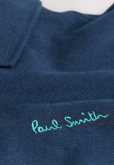 Tengerészkék galléros póló texturált anyagból. A mellrészen zölden hímzett "Paul Smith" felirattal.