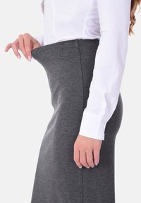 Gonna grigia in jersey con una texture liscia, dotata di una vita flessibile e una camicia bianca a contrasto con maniche lunghe e dettagli ai polsini.