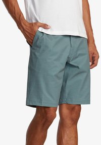 Shorts teal pour hommes en tissu léger, avec une coupe droite, des poches latérales et une texture subtile.
