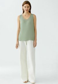 Un haut sans manches vert clair avec un col rond, associé à un pantalon blanc à jambes larges. Le tissu semble lisse et fluide sans motifs.