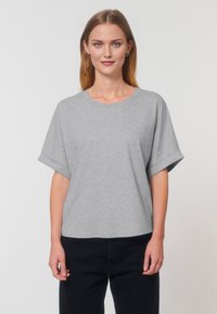 T-shirt gris à manches courtes en coton doux, avec un col rond et une coupe décontractée, associé à un pantalon noir.