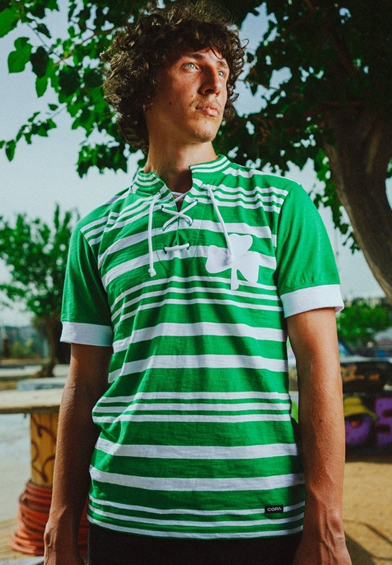 Groen en witte gestreepte short-sleeve shirt met een vetersluiting en een groot klavertje vier ontwerp op de voorkant. Gemaakt van katoenen stof.