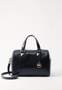 Sac à main en simili cuir noir avec une forme arrondie, accents en métal doré, deux poignées supérieures et une bandoulière amovible. Présente un charm logo.