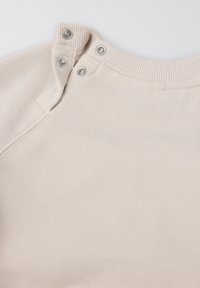 Beige sweatshirt met een geribbelde kraag, voorzien van drukknoopjes bij de hals. Zachte textuur, gladde stof en een eenvoudig ontwerp.