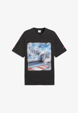 Maglietta nera Puma con grafica sfocata di uno pneumatico di una monoposto di Formula 1 su una pista da corsa sotto un cielo tempestoso con fulmini.