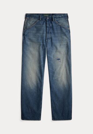 Sinised teksapüksid lõdva lõikega, millel on tuhmunud alad, plaastr vasakul reiel ja nähtav õmbluse detail.