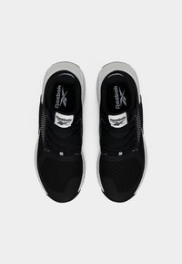 Ζευγάρι μαύρα και λευκά παπούτσια τρεξίματος Reebok, σε άποψη από πάνω σε λευκό φόντο, με το λογότυπο της μάρκας στη γλώσσα και στην εσωτερική σόλα.