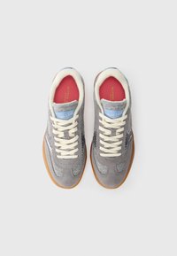 Sneaker grigie con tomaia in camoscio e feltro, lacci crema e un accento blu chiaro sul tallone, con suola in gomma e soletta rossa.