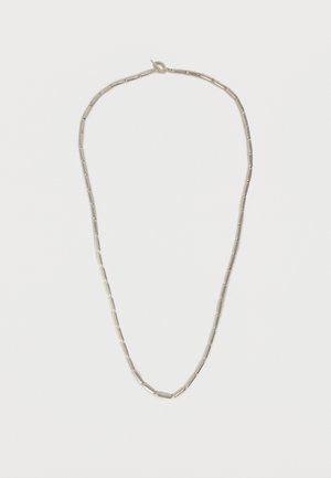 Collier en argent avec des perles cylindriques allongées espacées uniformément et une petite fermeture à crochet sur un fond blanc uni.