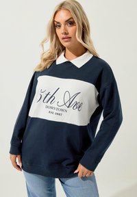 Marinblå och vit sweatshirt med krage, långa ärmar och tryckt text, med en avslappnad passform och mjuk tygtextur.