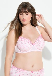 Vaaleanpunainen rintaliivi, jossa on brodeerattuja sydämiä ja naruja. Sisältää muotoillut kupit, säädettävät olkaimet ja koristeellisen keskikohdan nauhan. Sujuva pinta.