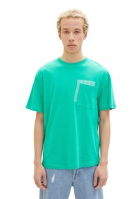 Turquoise cotton t-shirt with a round neckline, short sleeves, and a front pocket featuring a white geometric pattern.
