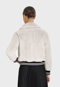 Bunda bomber z fleecu v světle šedé barvě, s jemnou texturou, širokým límcem, černobílými pruhovanými ribbovými manžetami a zkráceným střihem.