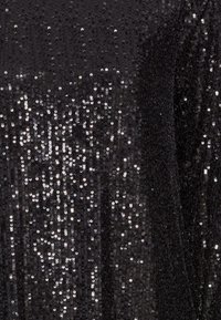 Svart paljettyg med en tät arrangemang av glänsande runda paljetter, vilket skapar en texturerad yta med varierande reflektioner och mönster.