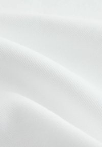 Tissu blanc texturé à surface lisse, présentant des motifs tissés subtils et des drapés doux. Le tissu semble léger et flexible.