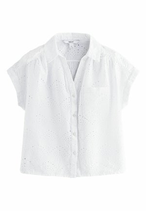 Blouse blanche à manches courtes avec un col, présentant des motifs en broderie et œillets, une fermeture à boutons et une poche sur la poitrine gauche.