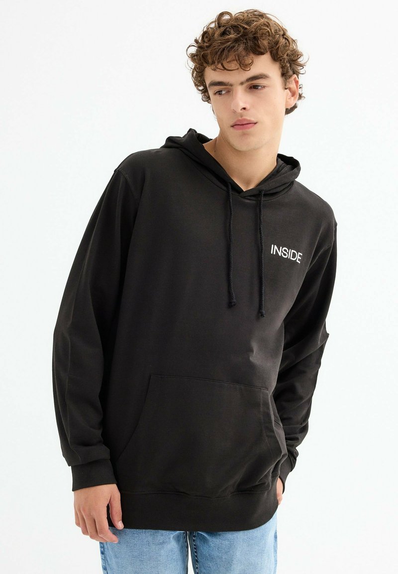 Sudadera negra de tela suave, con un bolsillo frontal y capucha con cordón, con el texto blanco "INSIDE" en el pecho. Diseño casual.