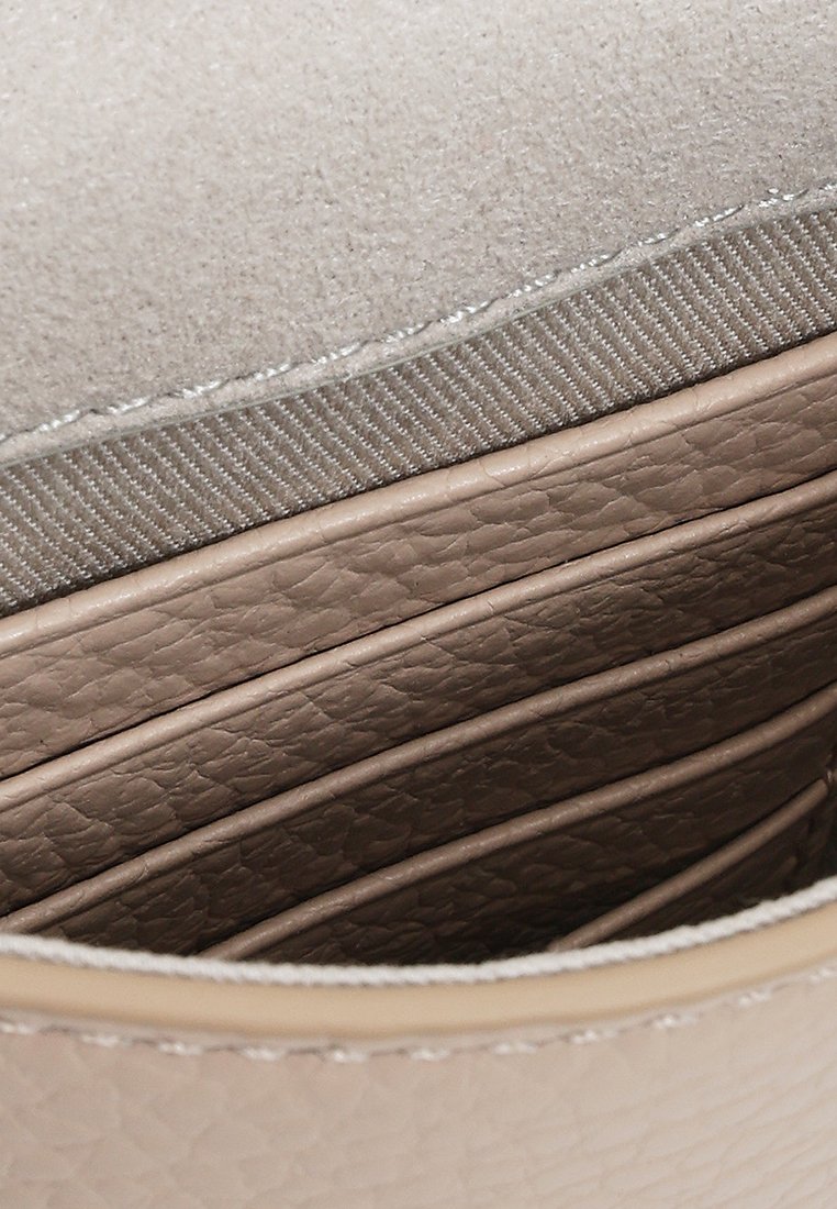 Beige Lederhandtasche mit glatter Textur im Inneren, die mehrere Kartenfächer und eine weiche Innenauskleidung aufweist. Dezente Nahtdetails sind sichtbar.