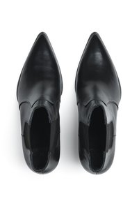 Stivaletti neri in pelle con punta affusolata, pannelli elastici laterali e una superficie liscia e lucida. Presentano un design con bordo ondulato nella parte superiore.