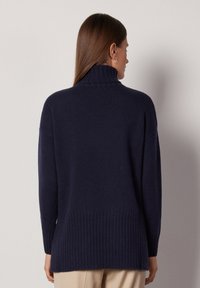 Marineblauer Strickpullover mit hohem Kragen, langen Ärmeln und geripptem Saum. Verfügt über einen lockeren Schnitt und einen weichen, strukturierten Stoff.