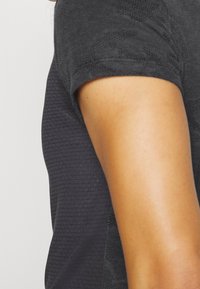 Grå texturerad kortärmad topp med ribbat mönster och släta sidopaneler, utformad för en åtsittande silhuett.