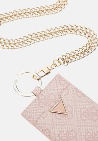 Jasnoróżowy portfel na karty z tłoczonym wzorem w kwiaty, ze złotą ramką, złotymi akcentami i trójkątnym logo z przodu.