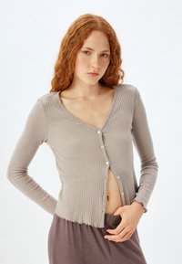 Grå ribbet cardigan med lange ærmer, V-hals og knaplukning. Stoffet virker blødt med en let struktureret overflade. Rynket kantdetalje.