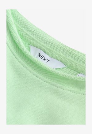 Světle zelené bavlněné tričko s kulatým výstřihem a texturovaným pleteným detailem, s bílou etiketou uvnitř se značkou "NEXT".