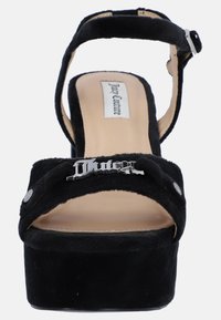 Sandalo platform in suede nero con cinturino alla caviglia regolabile, hardware con logo prominente e soletta beige liscia. Design con punta arrotondata e accenti sottili.