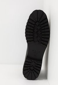 Suela de goma negra con profundas ranuras y un patrón elevado. Marca en relieve "WALK LONDON" cerca del talón. Tamaño 8 indicado.