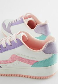 Weiße Sneakers mit lila, rosa und türkisfarbenen Akzenten; Glitzerdetails an der Seite, strukturierte Elemente und passende pastellfarbene Schnürsenkel.