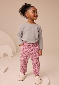 Svetlosivá košeľa s dlhým rukávom v kombinácii s ružovými nohavicami s leopardím vzorom. Mäkká textúra, voľný strih, elastický pás a biele chlpaté papuče.