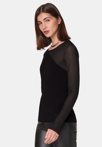 Schwarzes geripptes Langarmoberteil mit strukturiertem Design; verfügt über einen runden Halsauschnitt und eine figurnahe Silhouette. Abgerundet mit transparenten Ärmeln.