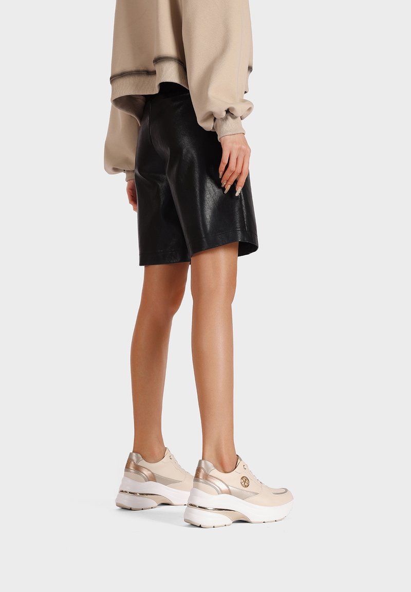 Sneakers in pelle beige con dettagli metallici e una suola bianca spessa. Abbinate a un felpa oversize beige e pantaloni in pelle nera.