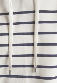 Witte hoodie met marineblauwe strepen, voorzien van een gestructureerde stof, trekkoorden en metalen aglets. Klassiek ontwerp dat de horizontale lijnen benadrukt.