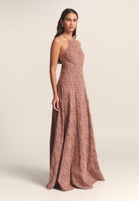 Ilga suknelė iš minkšto rožių spalvos audinio su gėlių raštu, aukštu galiuku, prigludusiu liemeniu ir laisvai krentančia sijono dalimi. Lygi tekstūra, minimalūs metaliniai elementai.