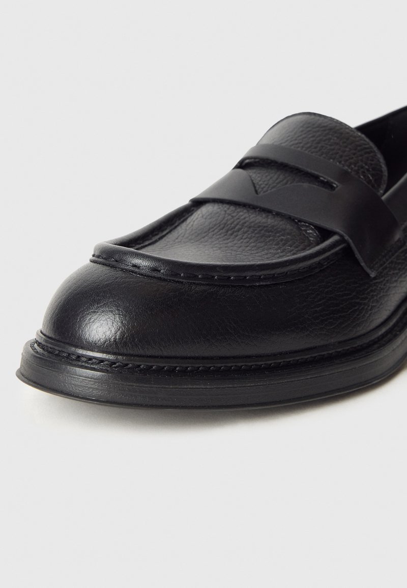 Schwarzer Lederloafer mit glatter Textur, ausgestattet mit einem Riemen über dem Spann und einer runden Zehenpartie. Ausgearbeitete Naht entlang der Sohle.