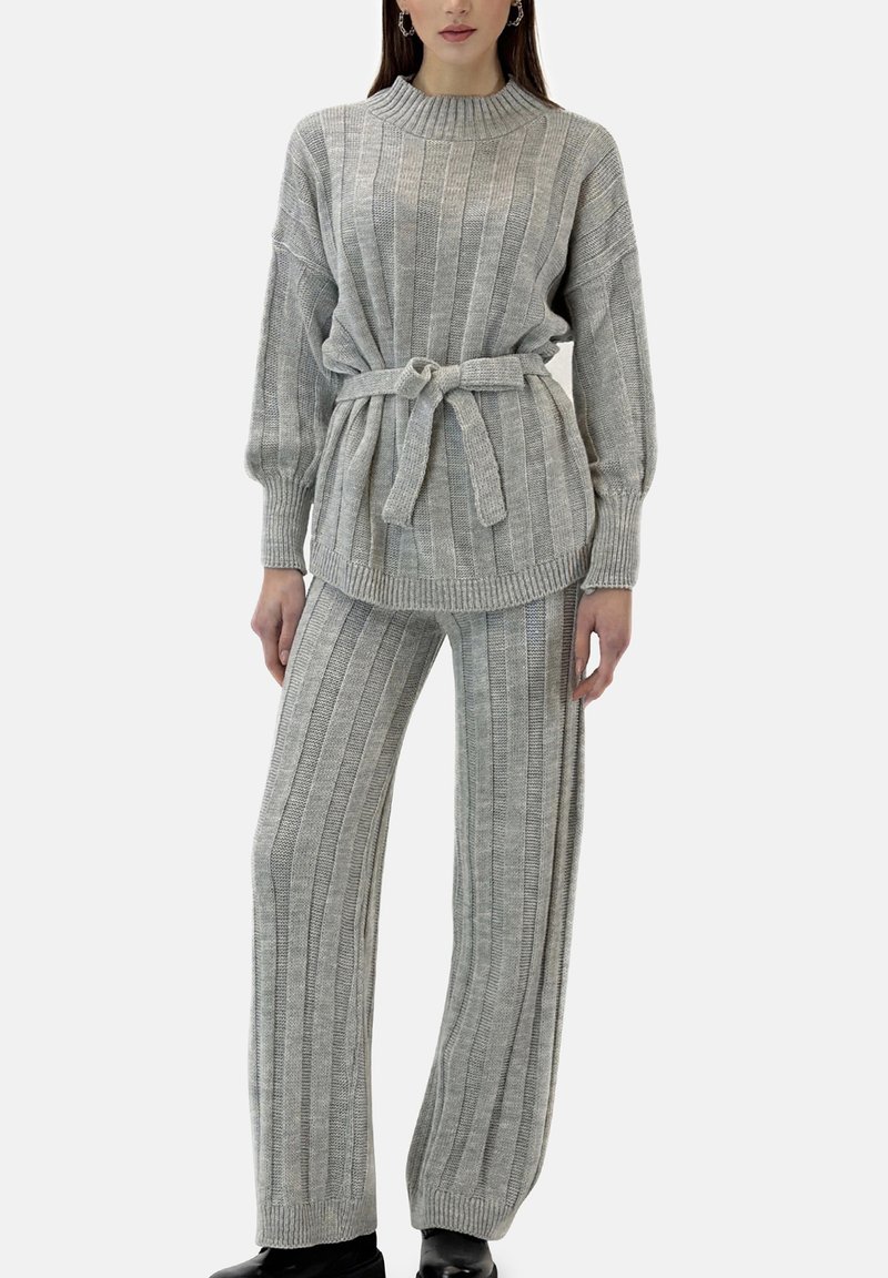 Conjunto de suéter y pantalones de punto gris con canalé vertical, corte holgado, cuello alto y detalle de cintura con cinturón. Textura suave y mangas largas.