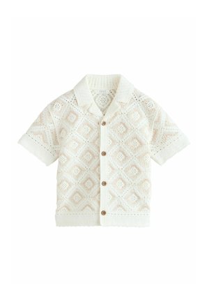 Chemise blanche à manches courtes avec boutons, motif losanges tricoté et petits boutons marron, avec un col ouvert.