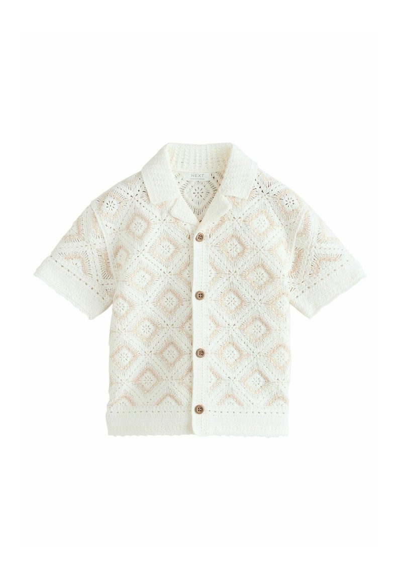 Chemise blanche à manches courtes avec boutons, motif losanges tricoté et petits boutons marron, avec un col ouvert.